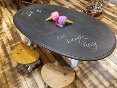 a black table with chalk writing on it and some flowers sitting on top of it