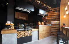 the interior of a coffee shop with wood stacked on the counter and lights hanging from the ceiling