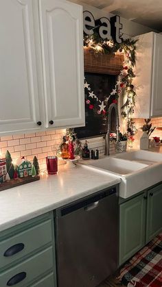 a kitchen decorated for christmas with garland and lights on the counter top, sink area