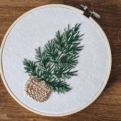 a close up of a embroidery on a hoop with a pine tree in the center