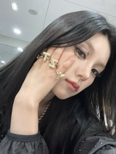 a woman with long black hair and gold rings on her fingers is posing for the camera