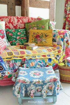 a colorful couch with many pillows on it and a basket in front of the couch