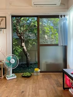 a living room with a fan, table and window