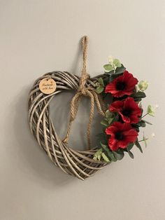 a heart shaped wreath with red flowers hanging on the wall next to a sign that says, i love you