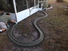 a man is working on a tire track in the grass near a tree and building