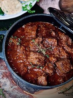 a pot filled with meat and sauce on top of a table