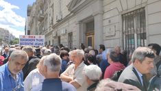 a large group of people standing in front of a building with signs on the doors