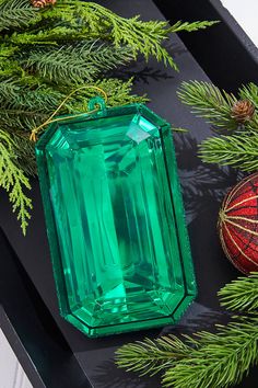 an emerald colored stone sitting on top of a table next to christmas ornaments and pine branches