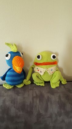 two crocheted stuffed animals sitting next to each other on a couch in front of a white wall