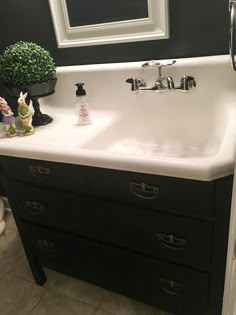 a white sink sitting under a mirror next to a black cabinet and counter top in a bathroom