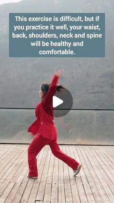 a woman in a red suit is dancing on a wooden deck with mountains in the background