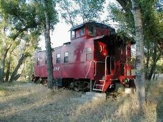 an old red train car sitting in the woods