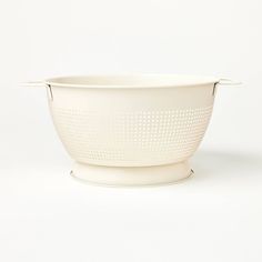 a large white colander bowl with perfored design on the bottom and handles