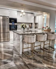 a kitchen with marble floors and stainless steel appliances, along with two bar stools