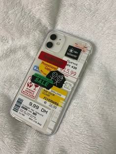 an iphone case with stickers on it sitting on a white sheet covered bedding