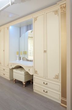 a white dressing room with an armoire and mirror on the wall next to it