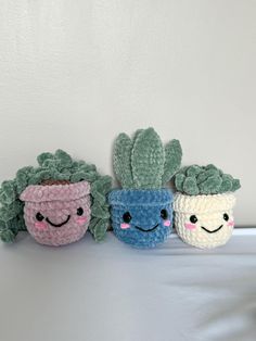 three crocheted potted plants with faces drawn on them