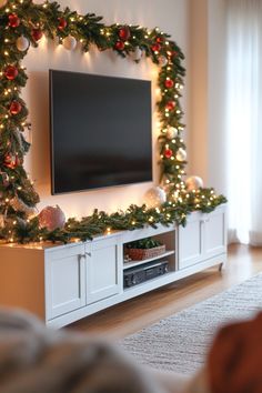 a living room with christmas decorations on the wall and a flat screen tv mounted above it