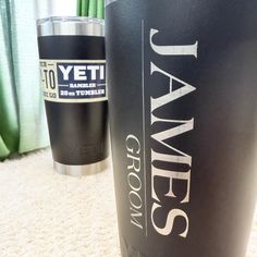 two black tumblers sitting on top of a carpeted floor next to green curtains