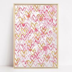 a pink and gold painting with hearts on it in a golden frame against a white wall