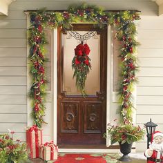 a front door decorated for christmas with wreaths and poinsettis on it