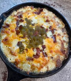 an omelet with bacon and cheese in a cast iron skillet on a table