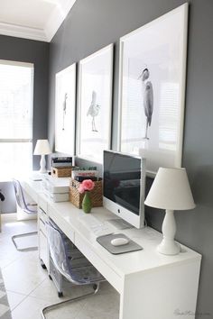 a white desk with two computer monitors on top of it and a lamp next to it