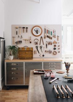 a kitchen with lots of tools hanging on the wall and wooden drawers in front of it