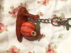 a red dog figurine is attached to a metal keychain on a flowered tablecloth