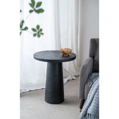 a black table sitting in front of a window next to a gray chair and white curtains