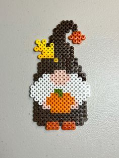 an image of a penguin made out of perler beads on a white wall with orange and yellow accents