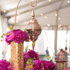 pink flowers and gold vases on a table with arabic writing in the middleground