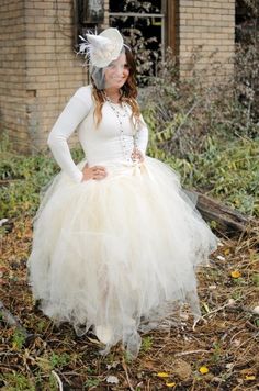 a woman wearing a white dress and hat standing in front of an old brick building