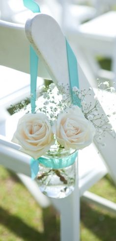 a white chair with flowers on it and some blue ribbon hanging from the armrests