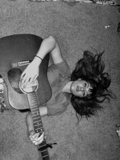 a woman laying on the floor with a guitar