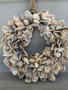 a wreath made out of seashells hangs on the front door with a rope