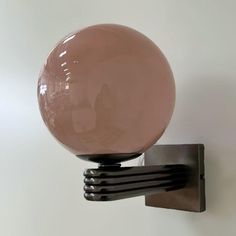 a glass ball mounted to the side of a metal wall hook on a white wall