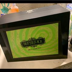 a green and black box sitting on top of a counter next to a bottle of liquid