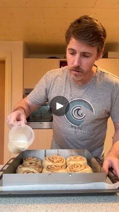 a man pouring milk into a pan filled with pastries