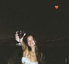 a woman holding up a wine glass at night