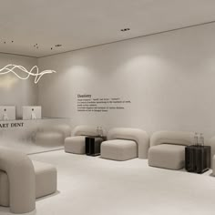 an empty room with white furniture and lights on the ceiling, in front of a display wall