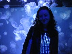 a woman standing in front of a wall full of jellyfish