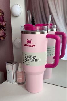 the pink tumbler cup is next to two other cups