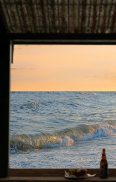 there is a bottle that is sitting on the window sill next to the ocean