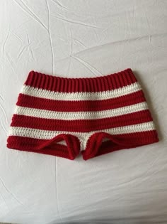 a red and white knitted shorts laying on top of a bed