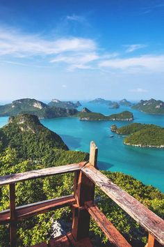 a wooden bench sitting on top of a lush green hillside next to the ocean and mountains