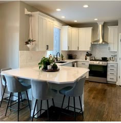 a kitchen with white cabinets and an island in the middle, surrounded by bar stools