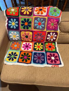 a crocheted granny blanket on a chair with flowers in the center and squares around it