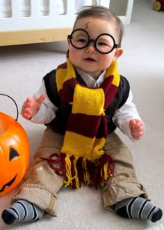 a baby wearing glasses sitting next to a pumpkin