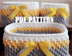 two gray and yellow baskets with bows on the handles, one is made out of yarn